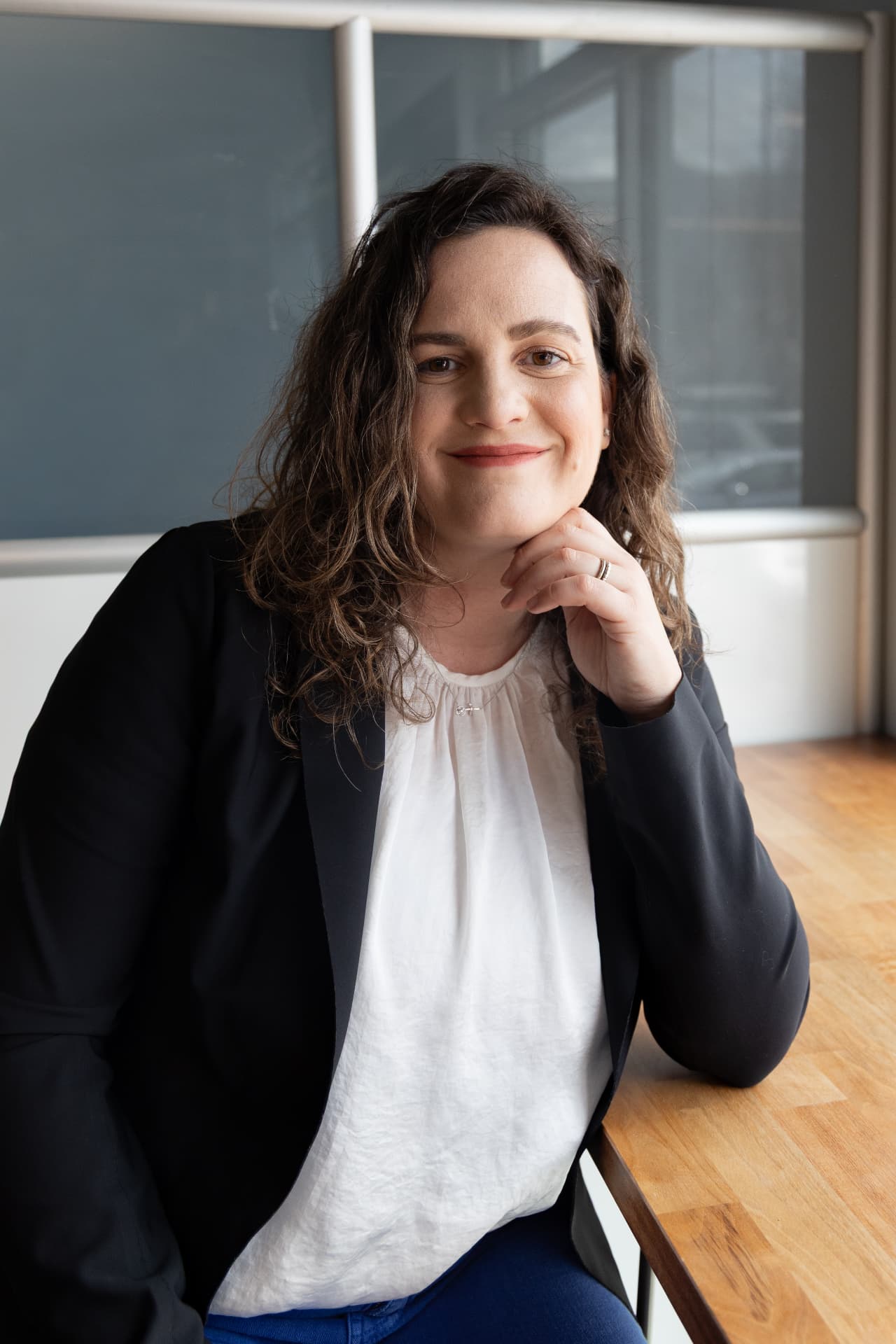 Monica Giannobile wearing a black suit jacket, seated at a table